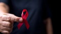 The red ribbon stick on black T-shirt. A person has a ribbon hang on shirt. The ribbon is the symbol of prevention HIV day. The