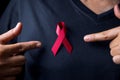 The red ribbon stick on black T-shirt. A person has a ribbon hang on shirt. The ribbon is the symbol of prevention HIV day. The