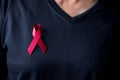 The red ribbon stick on black T-shirt. A person has a ribbon hang on shirt. The ribbon is the symbol of prevention HIV day. The