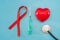 Red ribbon, syringe and heart on blue background with copy space for text. World AIDS Day, healthcare and medical concept Royalty Free Stock Photo