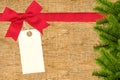 Red ribbon with a tag and christmas tree branch on wooden background Royalty Free Stock Photo