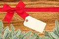 Red ribbon with a tag and christmas tree branch on wooden background Royalty Free Stock Photo