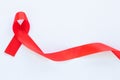 Red ribbon on white fabric background with copy space, symbol for the solidarity of people living with HIV/AIDS, and for the Royalty Free Stock Photo