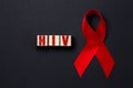 Red ribbon and wooden cubes with the word HIV on a black background. Close up. Flat lay. The concept of world AIDS day Royalty Free Stock Photo