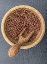 Red rice and olive wood scoop in a wooden bowl on black background of slate or stone Royalty Free Stock Photo