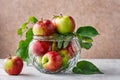 Red ripe apples with green leaves in a glass vase stand on the table. Fresh fruits, autumn harvest Royalty Free Stock Photo