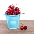 red ripe cherries in blue bucket on wooden table, isolated on white background, close up Royalty Free Stock Photo