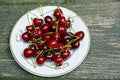 Red ripe cherries on a white plate on a wooden gray table Royalty Free Stock Photo