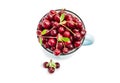 Red ripe cherry in a blue mug and three berries in front, top view. Sweet tasty fruits with water droplets in a cup isolated Royalty Free Stock Photo