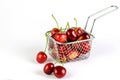 Red ripe cherry in the metal kitchen basket on the white background closeup. Healthy fruit eating