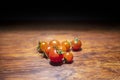 Red ripe cherry tomatoes sitting on a wooden bench with a black background Royalty Free Stock Photo