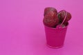 Red ripe fresh strawberries on a pink background lies in a pink bucket. spilled from a bucket of ripe strawberries