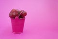 Red ripe fresh strawberries on a pink background lies in a pink bucket. spilled from a bucket of ripe strawberries.