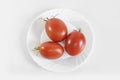 Red ripe juicy tomatoes on a white plate. Light gray background