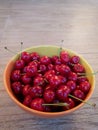 Red ripe sweet cherry in a yellow plate on a biege background. sweet summer