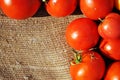 Red ripe tomatoes on a rough texture sackcloth background, corner horizontal frame, close up organic texture background Royalty Free Stock Photo