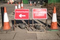 Red road traffic signs saying Footway Closed and directing Pedestrians with an arrow. Traffic cones used to block pavement