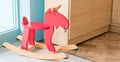 Red rocking horse toy for kid in home living room, cheerful riding stuff for children playing on the wooden floor in nursery, Royalty Free Stock Photo