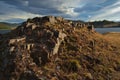 Red rocks stones shore of bay lake Baikal with yellow dry grass in autumn. Blue water, clouds Sunset light.