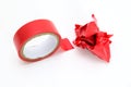 Red roll and a lump of crumpled used electrical sticky isolation duct tape on white background