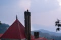 Red roof and chimney of a building shot against mountains and a