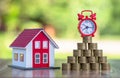 Red roof house And there are coins stacked with a red alarm clock placed on the pile of coins.Financial investment accounting Royalty Free Stock Photo