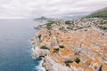 Red roofs of ancient houses behind high fortress walls on the seashore. Dubrovnik, Croatia. Drone