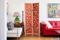 red room divider with oriental artwork against a white wall