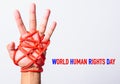 Red rope on lift hand with WORLD HUMAN RIGHTS DAY text on white background, Human rights day concept Royalty Free Stock Photo