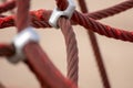 Red rope sections fastened with a metal clamp and a brown sand background Royalty Free Stock Photo