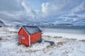 Red rorbu house shed on beach of fjord, Norway