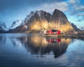 Red rorbuer and snowy rocks lighted by sun, blue sea at sunset