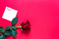 Red rose on red background with copyspace and sticker with a paper clip and heart, a reminder on a note sheet. A gift for a woman Royalty Free Stock Photo