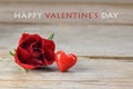 Red rose blossom and a heart shape from glass on rustic wood, text Happy Valentine`s Day, love concept with copy space Royalty Free Stock Photo