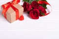 Red rose bouquet with red heart and gift box on white wood background