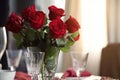 red rose bouquet in vase on dining table, setting the scene for a romantic dinner Royalty Free Stock Photo