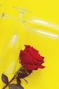 A red rose flower and two wine glasses lie on a yellow background. Vertical photo, top view, flat lay, copy space Royalty Free Stock Photo