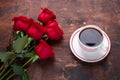 Red rose flowers bouquet and cup of coffee on wooden background. Valentine`s day greeting card Copy space Top view Royalty Free Stock Photo