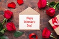 Red rose flowers bouquet, envelope and champagne glasses on wooden background. Valentine`s day greeting card Royalty Free Stock Photo