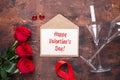 Red rose flowers bouquet, envelope and champagne glasses on wooden background. Valentine`s day greeting card Royalty Free Stock Photo