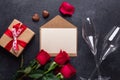 Red rose flowers bouquet, envelope, gift box, champagne glasses on black stone background Valentine`s day greeting card Royalty Free Stock Photo