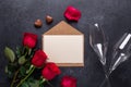 Red rose flowers bouquet, envelope, sweets, champagne glasses on black stone background Valentine`s day greeting card Royalty Free Stock Photo