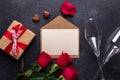 Red rose flowers bouquet, envelope, gift box, sweets, champagne glasses on black stone background Valentine`s day Royalty Free Stock Photo