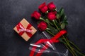 Red rose flowers bouquet, gift box, champagne glasses on black stone background Valentine`s day greeting card Royalty Free Stock Photo