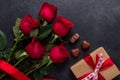Red rose flowers bouquet, gift box, chocolate sweets on black stone background Valentine`s day greeting card