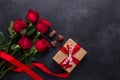 Red rose flowers bouquet, gift box, chocolate sweets on black stone background Valentine`s day greeting card Royalty Free Stock Photo