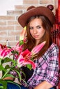 Attractive girl in a cowboy hat with straight long hair holds lily flowers in her hands Royalty Free Stock Photo