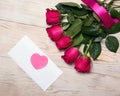 red rose flowers on wooden table with heart on white envelope. Romantic floral background for Valentine day greeting template Royalty Free Stock Photo