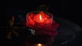 a red rose in a glass bowl with a candle in the middle of the bowl on a black table with a reflection of the candle in the glass Royalty Free Stock Photo