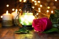 Red rose and lantern with lights on a wooden table Royalty Free Stock Photo